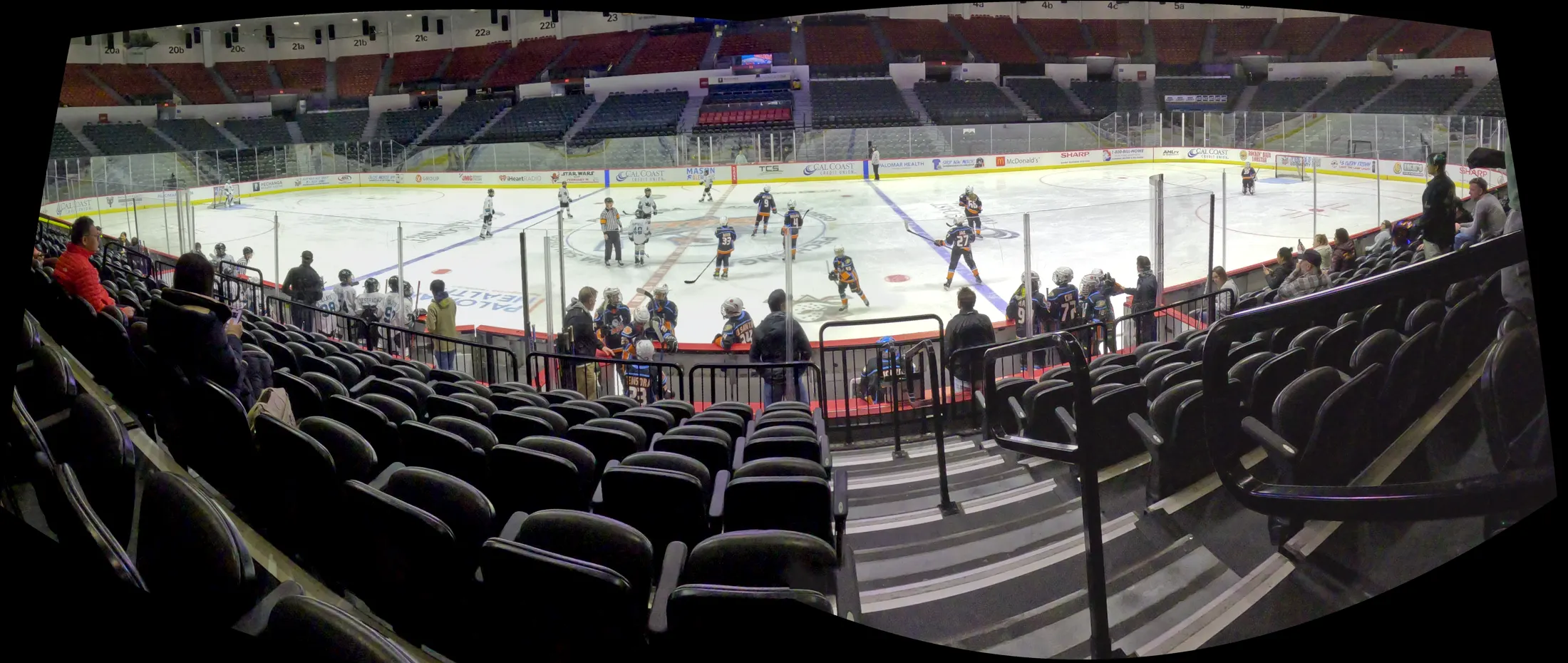 Wide panoramic view of a youth hockey game captured from the stands